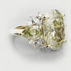 Gold ring with large yellow diamond and smaller white diamonds on a light gray background