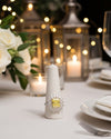 Yellow diamond ring on a white candle holder with a festive background of candles and lights.